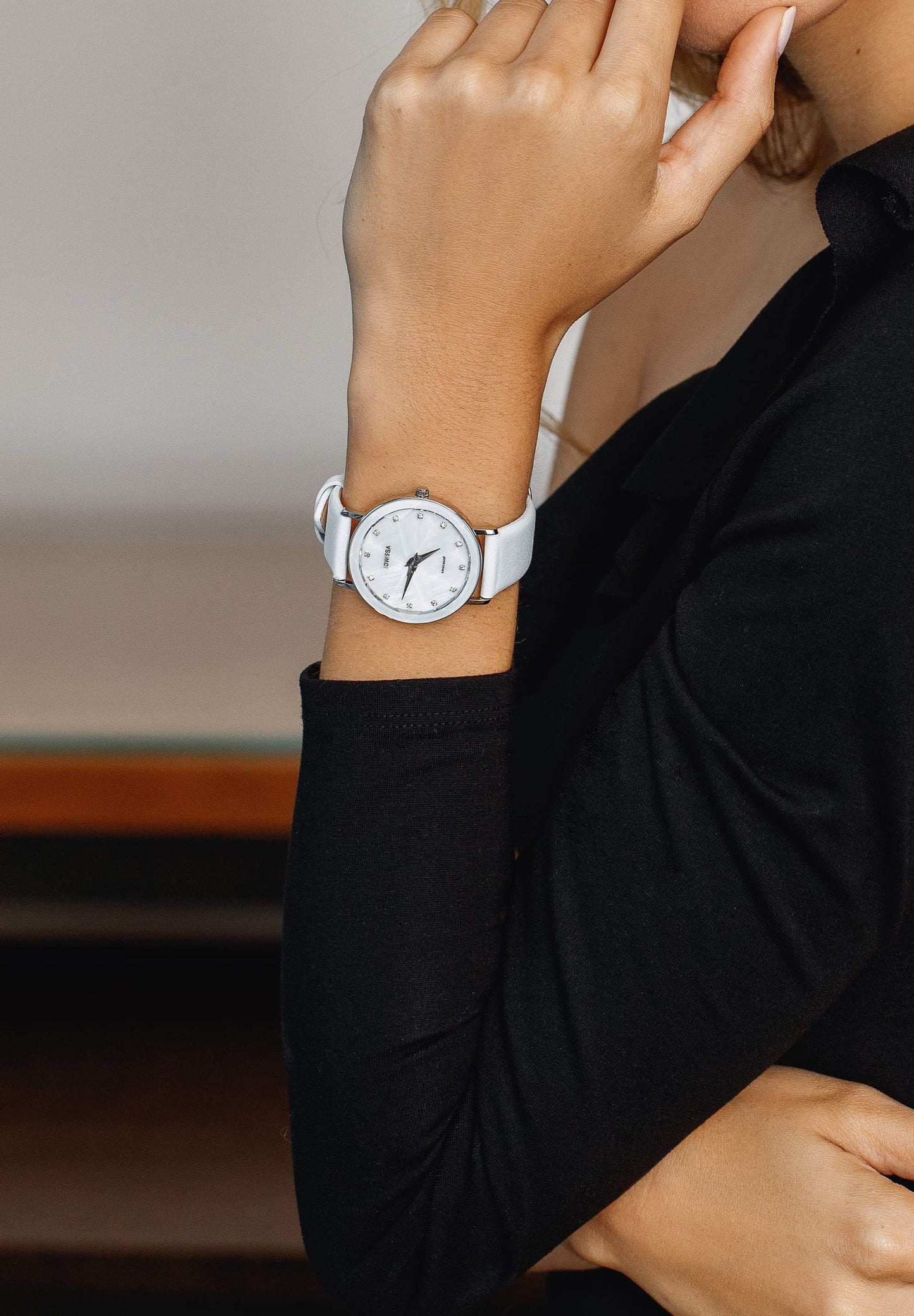 White facet watch worn by a girl with black shirt - the swiss watch has a white leather strap and silver details in the front - all swiss made watch for women