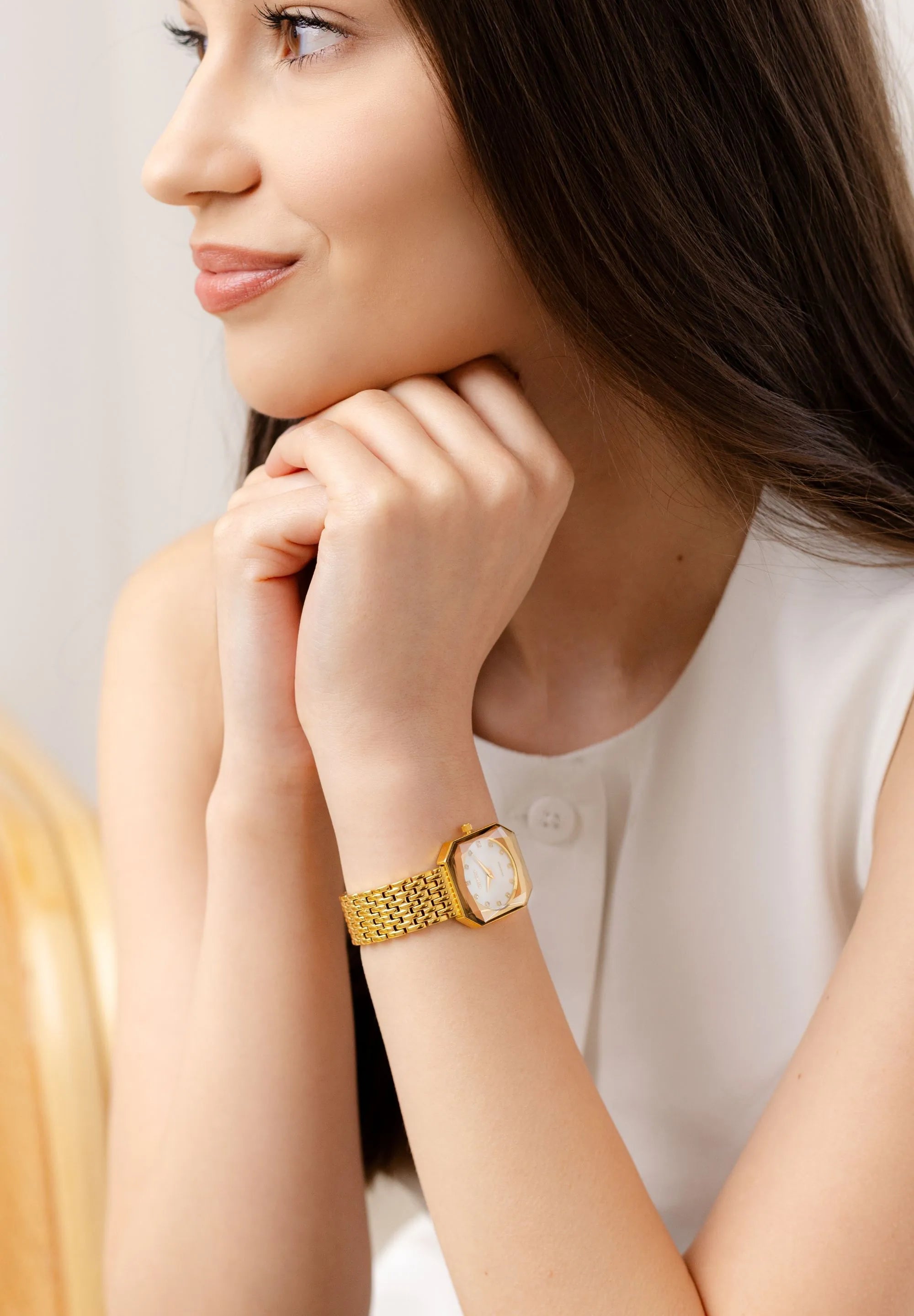 Gold women watch with a white mother of pear dial and 12 rhinestones as indexes. Stainless steel and all Swiss Made.

