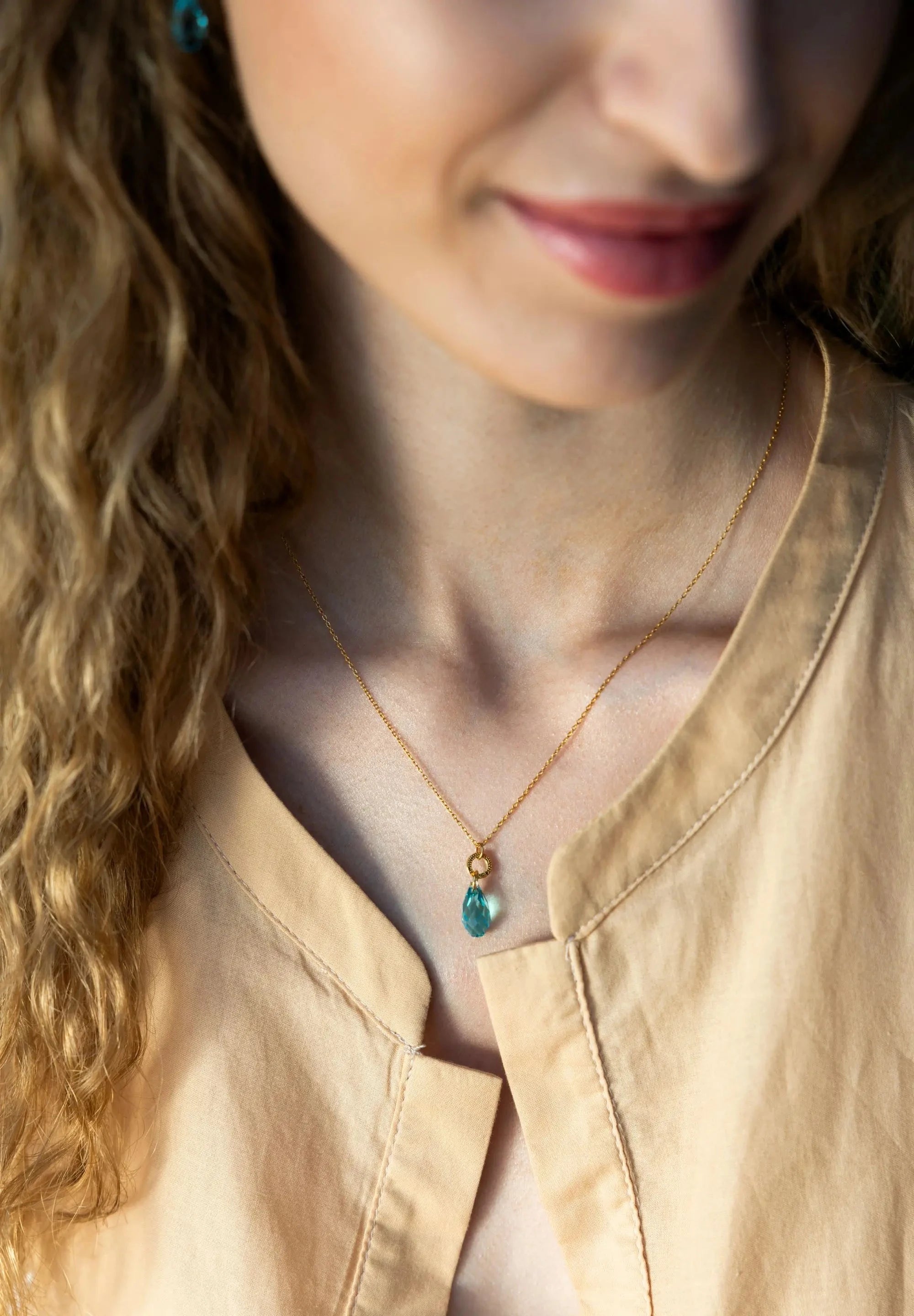 Stainless steel necklace in gold with a big 20mm Austrian crystal in turquoise, completing each outfit.