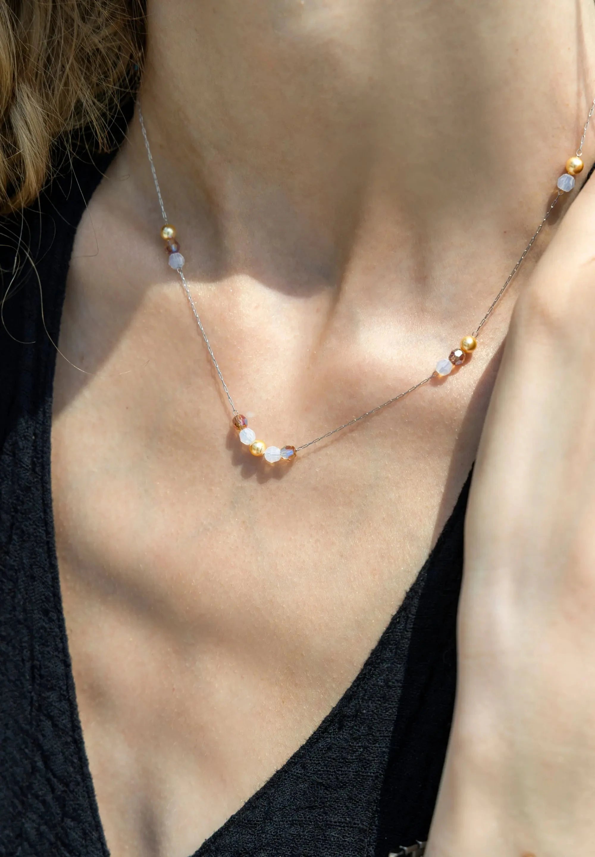 This necklace showcases a luminous clear/gold Austrian crystal, elegantly threaded onto a fine stainless steel chain.