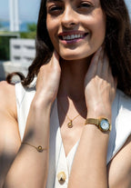 A happy woman wearing a nice jewelry set of the brand Jowissa. Made of stainless steel, in gold with glimmering cubic zirconia stones. The set contains a necklace, a bracelet and a golden faceted ladies watch of Jowissa.