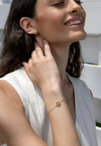 A woman who is wearing a jewelry set of Jowissa, made of stainless steel in gold. The Edelweiss is set within a circle made of cubic zirconia. The bracelet adorns her wrist niceley and so do the eaarrings, stunning.