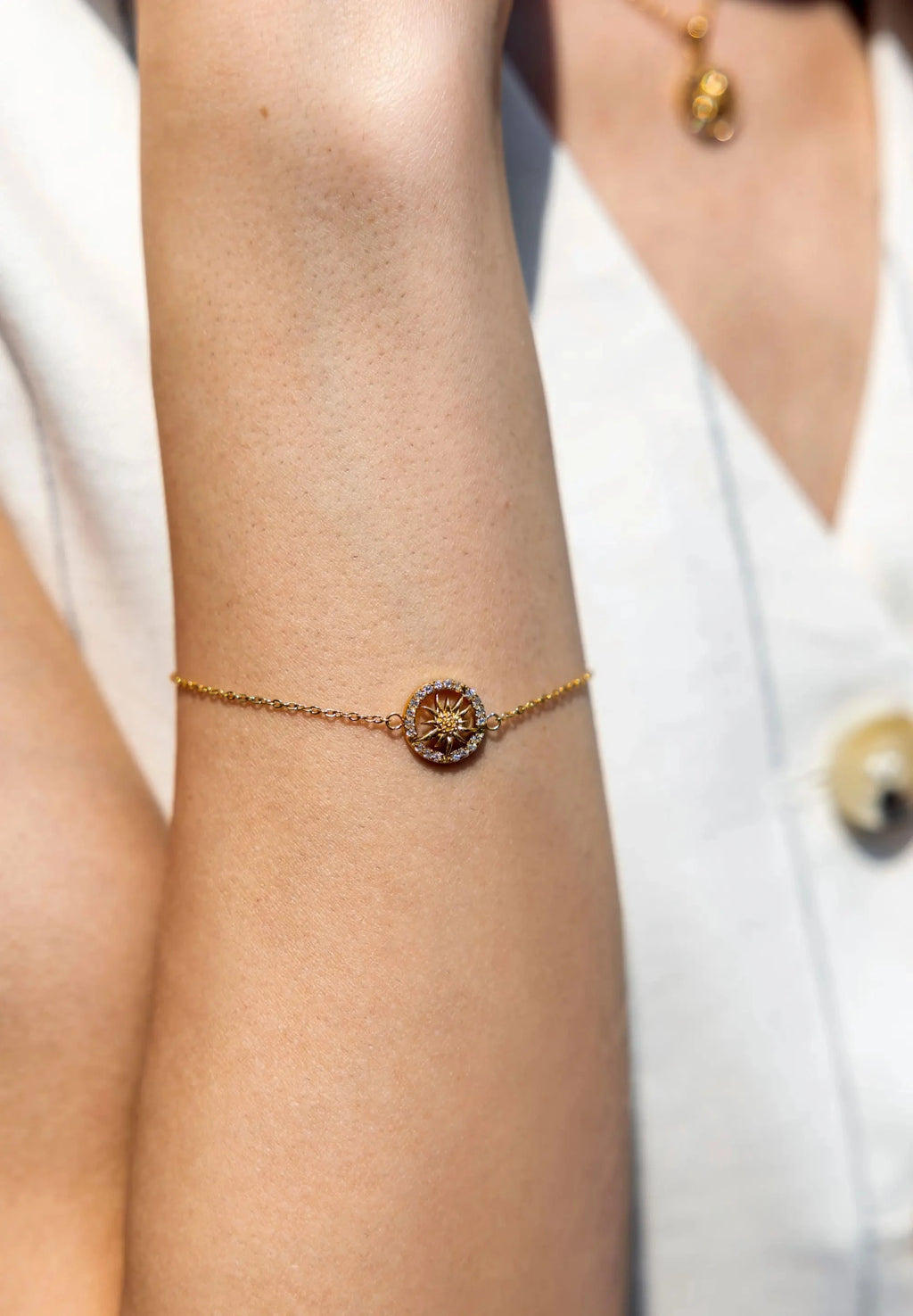 A golden stainless steel bracelet with a Edelweiss flower set within a circle of cubic zirconia stones.