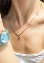 A lady wearing an Edelweiss Flower Necklace. This breathtaking pendant, adorned with 8 sparkling Cubic Zirconia stones and crafted from durable stainless steel is ads a touch of Swissness to your look.