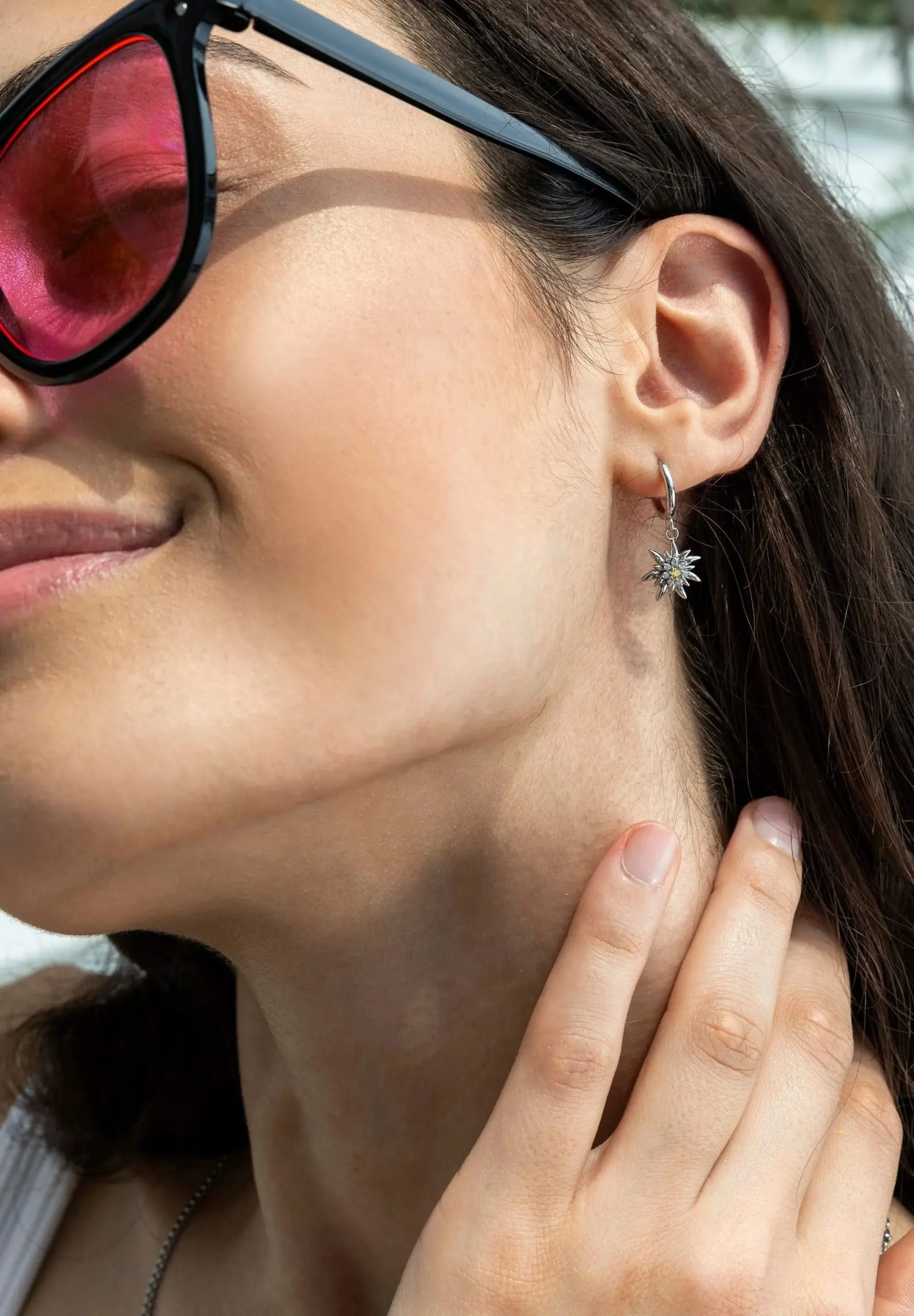 A happy woman wearing Jowissa Jewelry in stainless steel showing a Swiss flower called Edelweiss with 8 cubic zirconia.