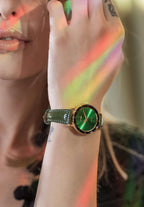 Green swiss watch for women - with green leather strap and black details on the front - worn by a women holding her hand on the face