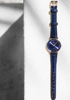 Swiss-made navy blue watch for women brings sophisticated style and a timeless color to your wrist. It features an elegant blue dial with golden accents on the hour hands and Roman numerals, adding a classic yet modern touch. The 30mm stainless steel case offers a delicate, refined profile, perfect for any occasion.