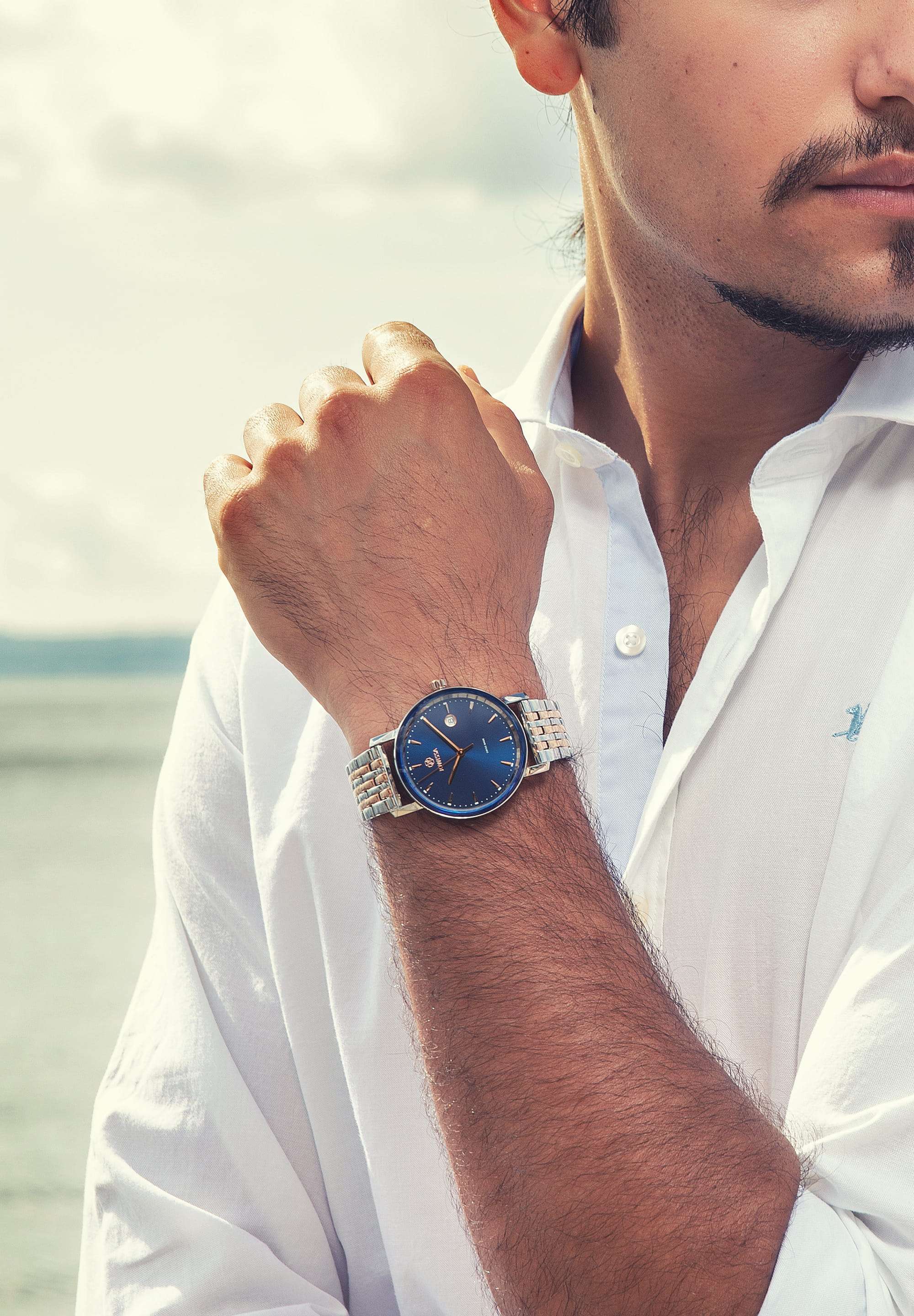 Swiss watch for men with blue dial in the front  - stainless steel - watch worn by a man wearing a white polo shirt - all swiss made watch