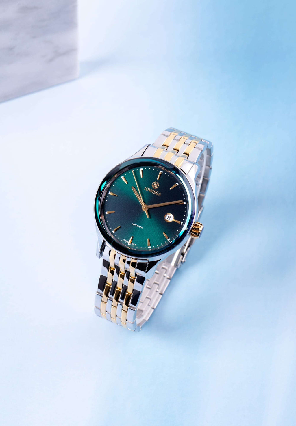 A men's watch featuring a vibrant green dial, complemented by a two-tone stainless steel bracelet. The Swiss automatic movement is visible through the back, and it includes a date display. All swiss made 