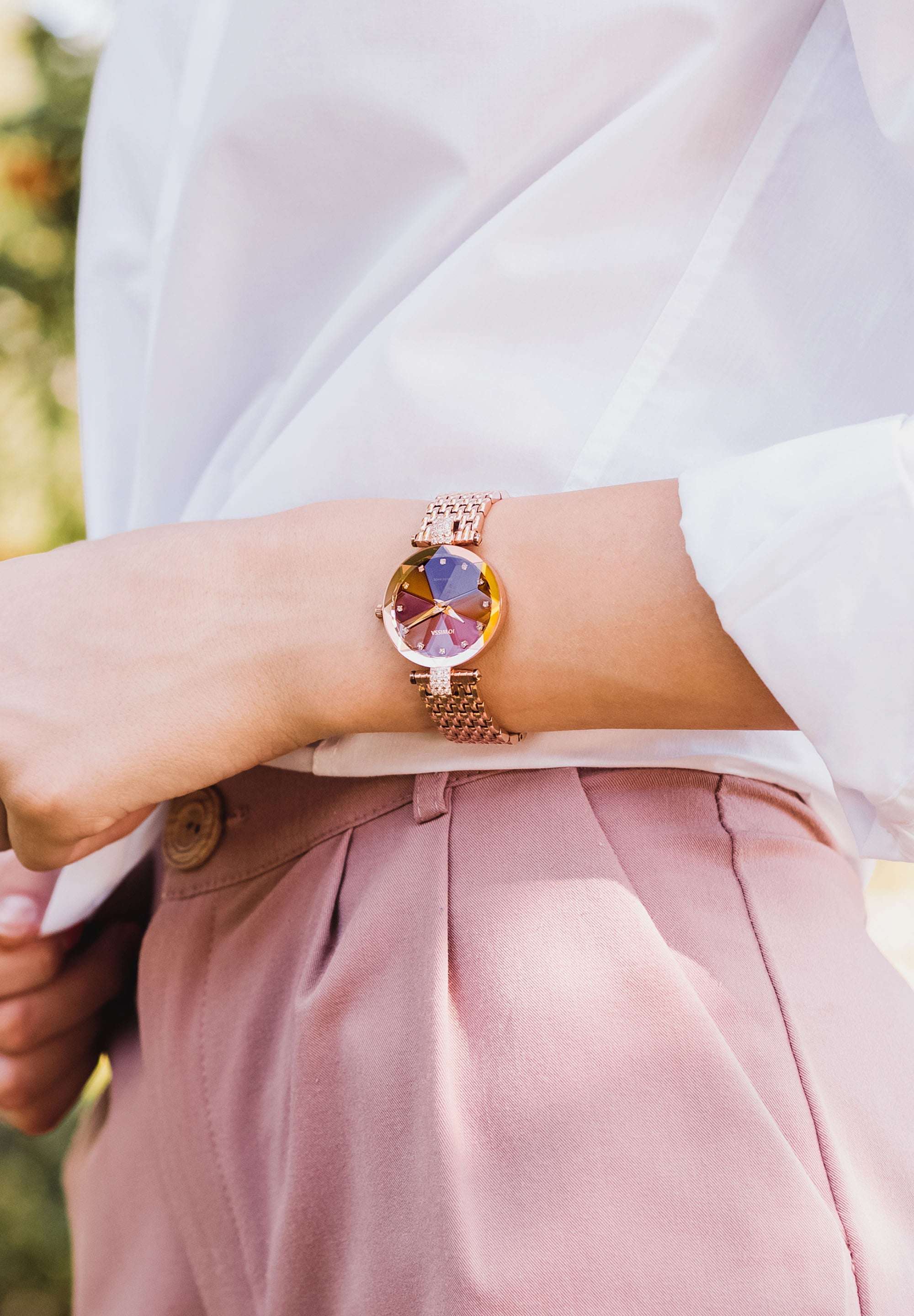 Swiss ladies watch worn by a woman with white shirt and pink pants - the watch is gold with red dial - all swiss made for women
