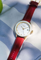 The J6.233.M Swiss-made watch features a gold-plated stainless steel case, white sunray dial with 12 rhinestone hour markers, and a diamond-cut bezel. Powered by a Ronda Swiss quartz movement, it includes a date window and Dauphine-style hands. The red genuine patent leather strap adds a bold touch. With 5 ATM water resistance