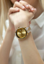 j6.242.m swiss watch worn by a girl placing the hand on the table - the watch has white and gold details - calendar window - from swiss - has a silicone band