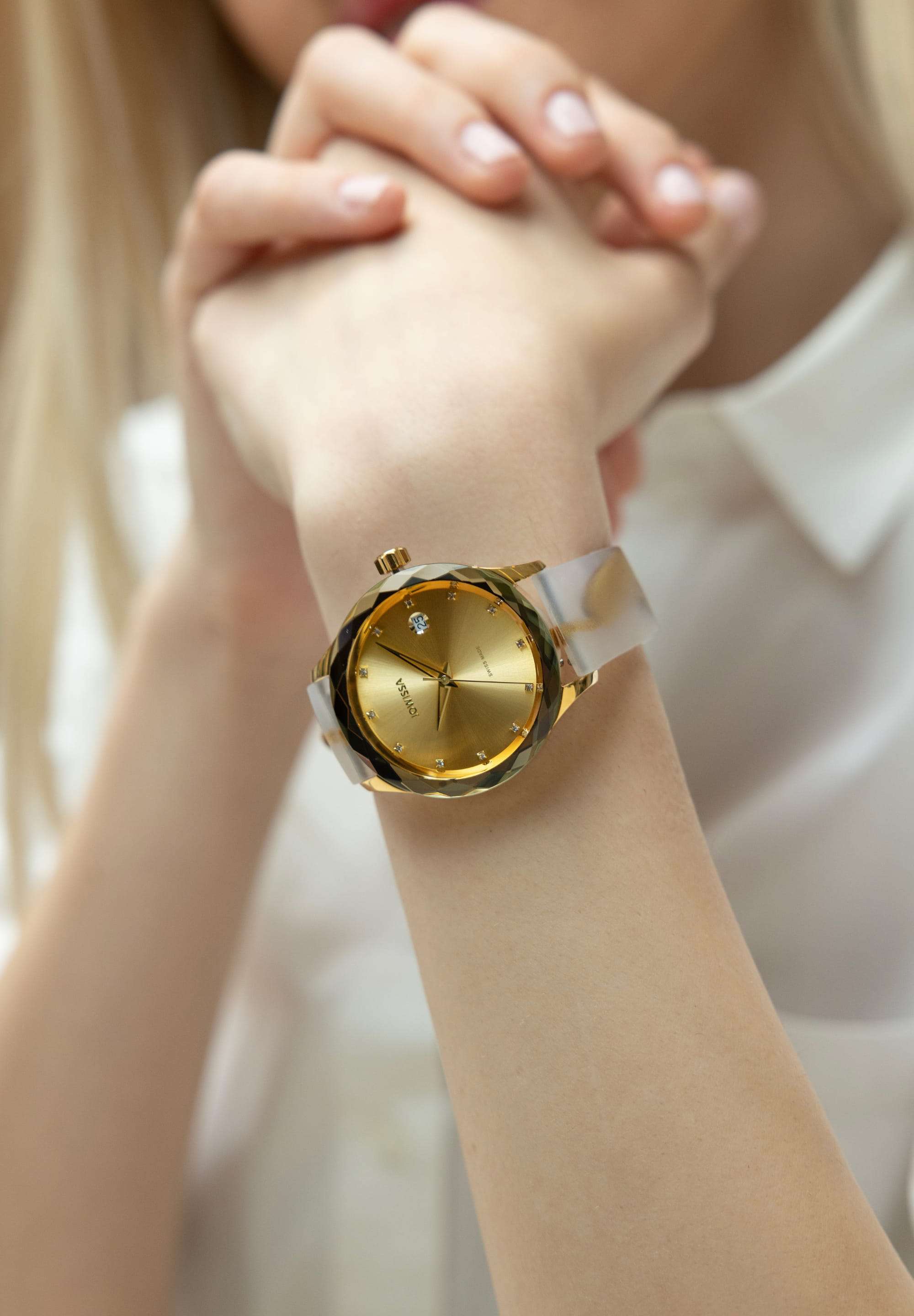 j6.242.m swiss watch worn by a girl placing the hand on the table - the watch has white and gold details - calendar window - from swiss - has a silicone band