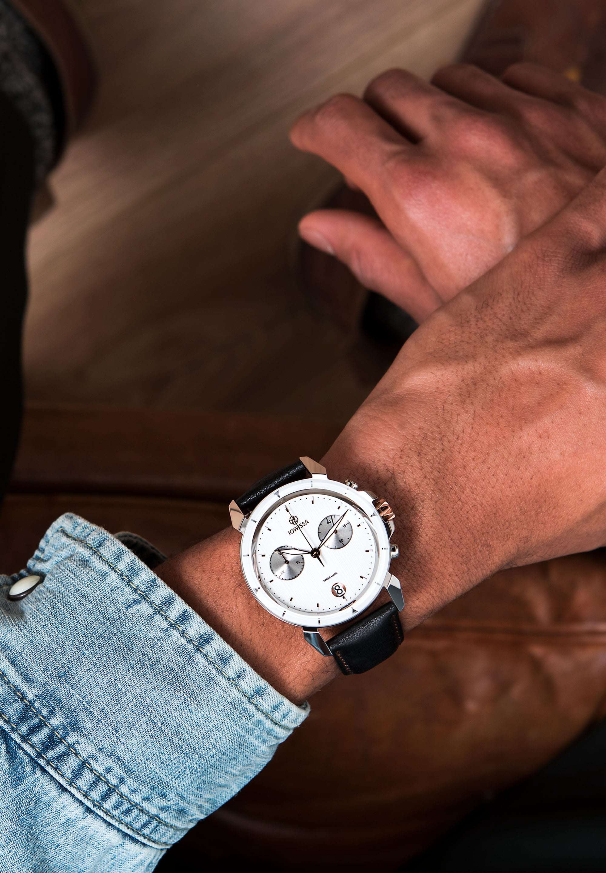 Black swiss made watch for men - worn by a man who has a jacket jeans and a swiss watch with white dial - all swiss made